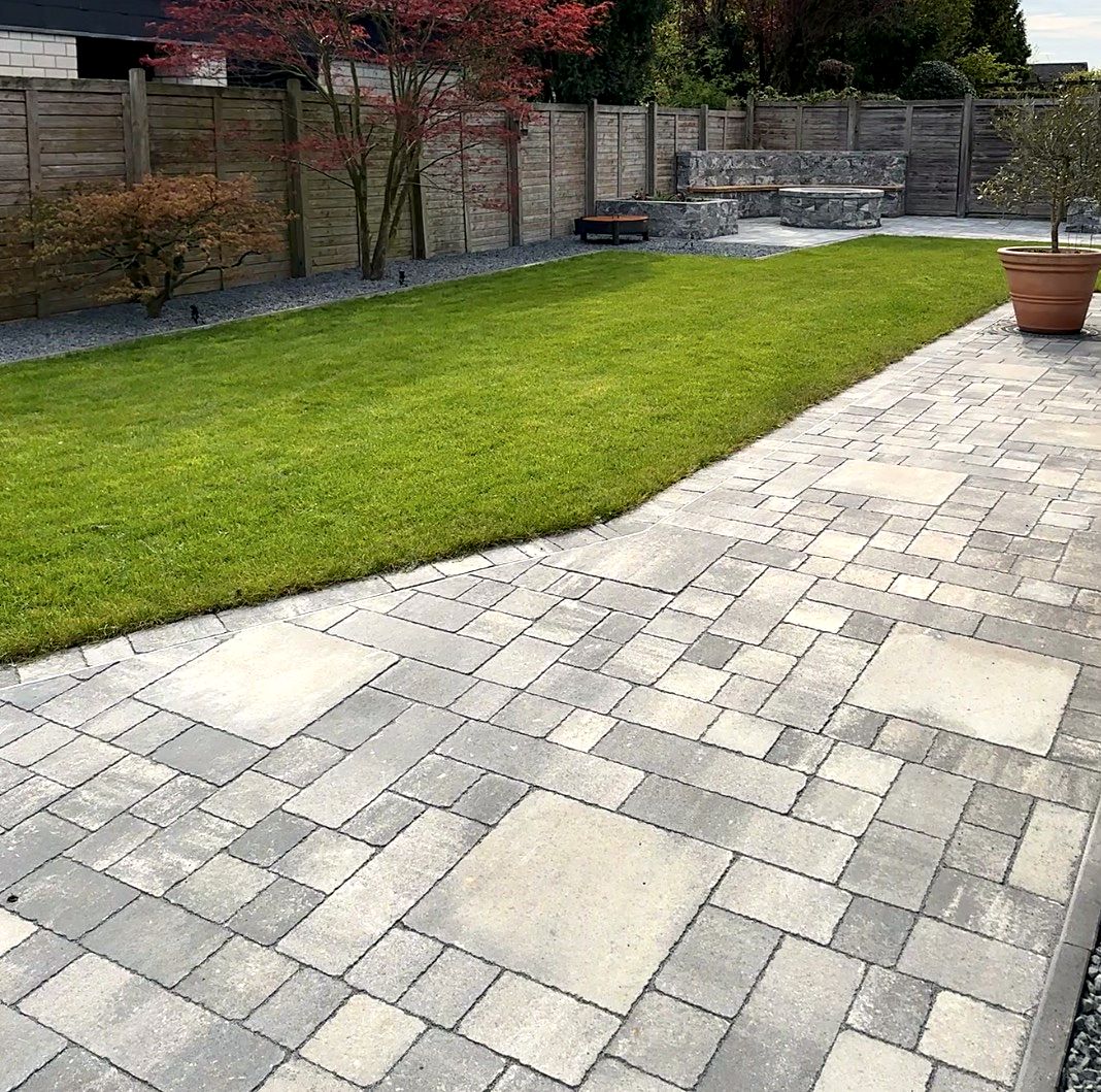 Neu gebauter Garten mit Terrasse aus Mehrformat-Pflaster, Rasen, Fächerahorn und Sitzmauer aus Naturstein