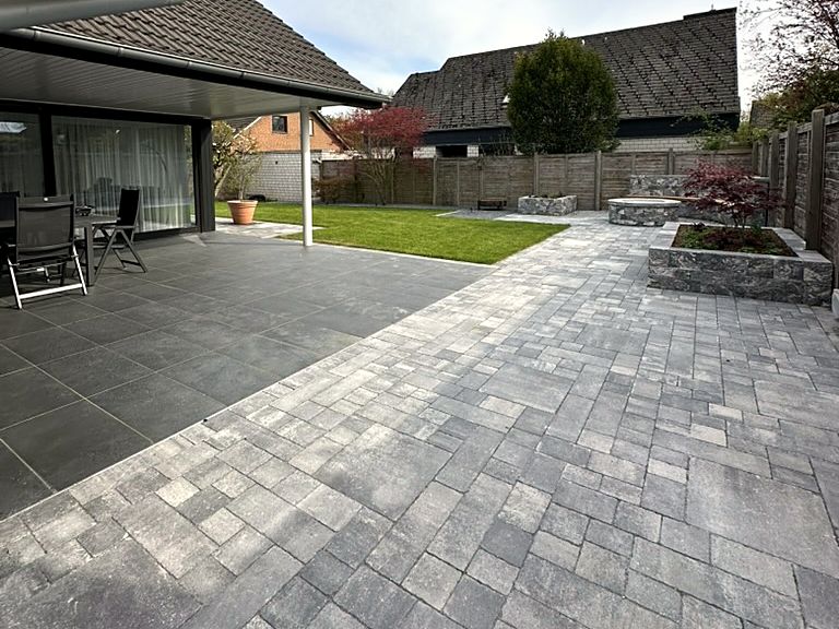 Überdachte Terrasse und Pflasterfläche mit Hochbeeten
