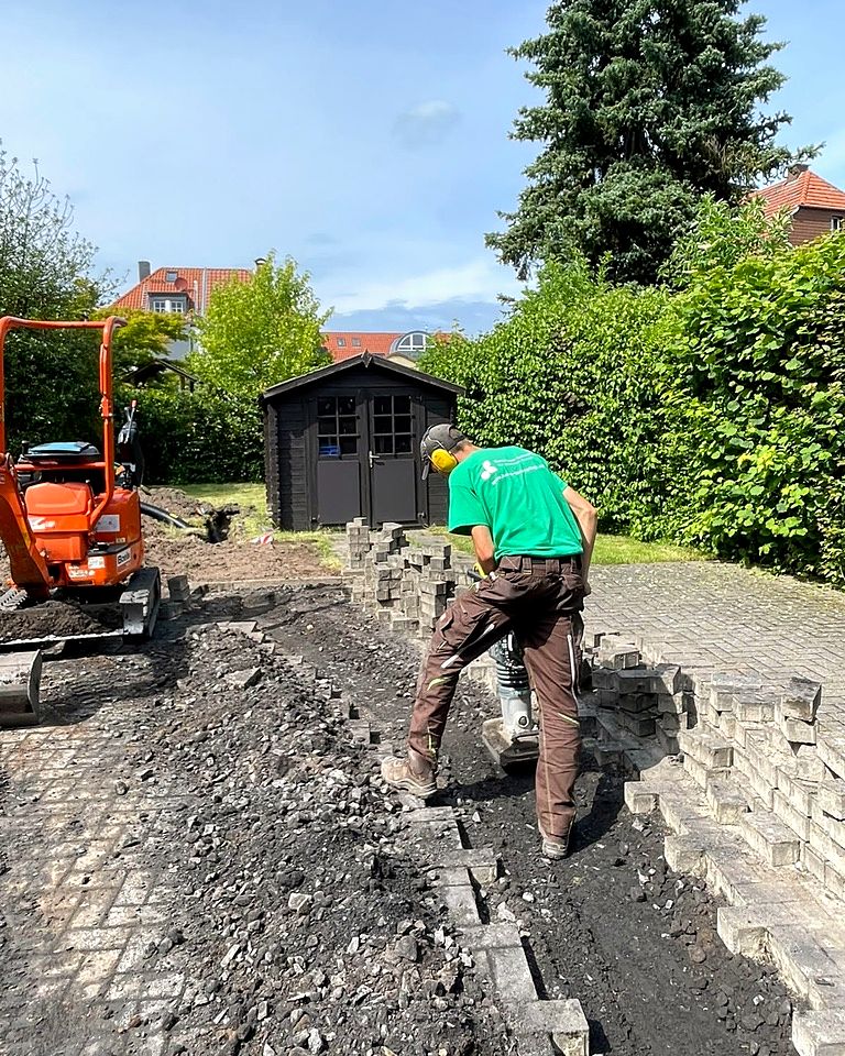 Mitarbeiter von Loose beim Verdichten des Unterbaus mit der Rüttelplatte, daneben der Minibagger